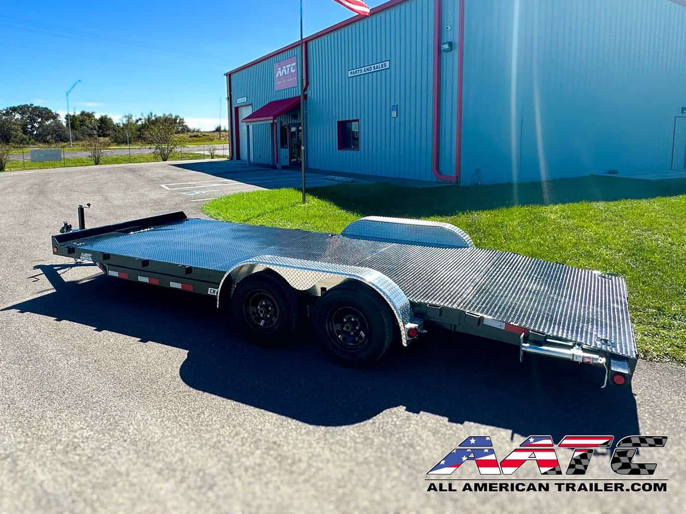 A PJ 20-foot steel deck car hauler trailer, model CH-202-SIR, designed for efficient vehicle transportation. This PJ Trailer features a 4-foot dovetail with 5-foot slide-in ramps, making it easy to load and unload vehicles. With a 3.5-ton capacity, a 7,000 GVWR, electric brakes, and a black finish, it's a durable and practical choice for car hauling. The bumper pull design allows for convenient towing.