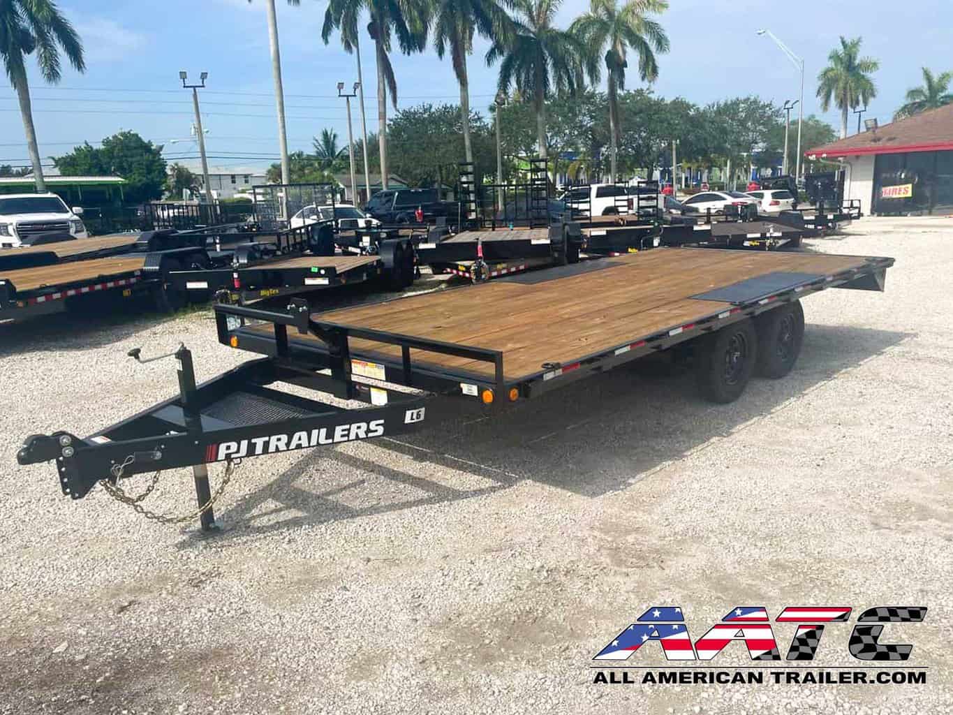 A black PJ 18-foot deckover equipment trailer with a 9,899 GVWR. This PJ Trailer features slide-in ramps, making it easy to load and unload equipment. It is a bumper pull hitch type trailer with electric brakes for enhanced safety. The PJ Deckover Trailer is designed for heavy-duty hauling and is part of the renowned PJ Trailers lineup.